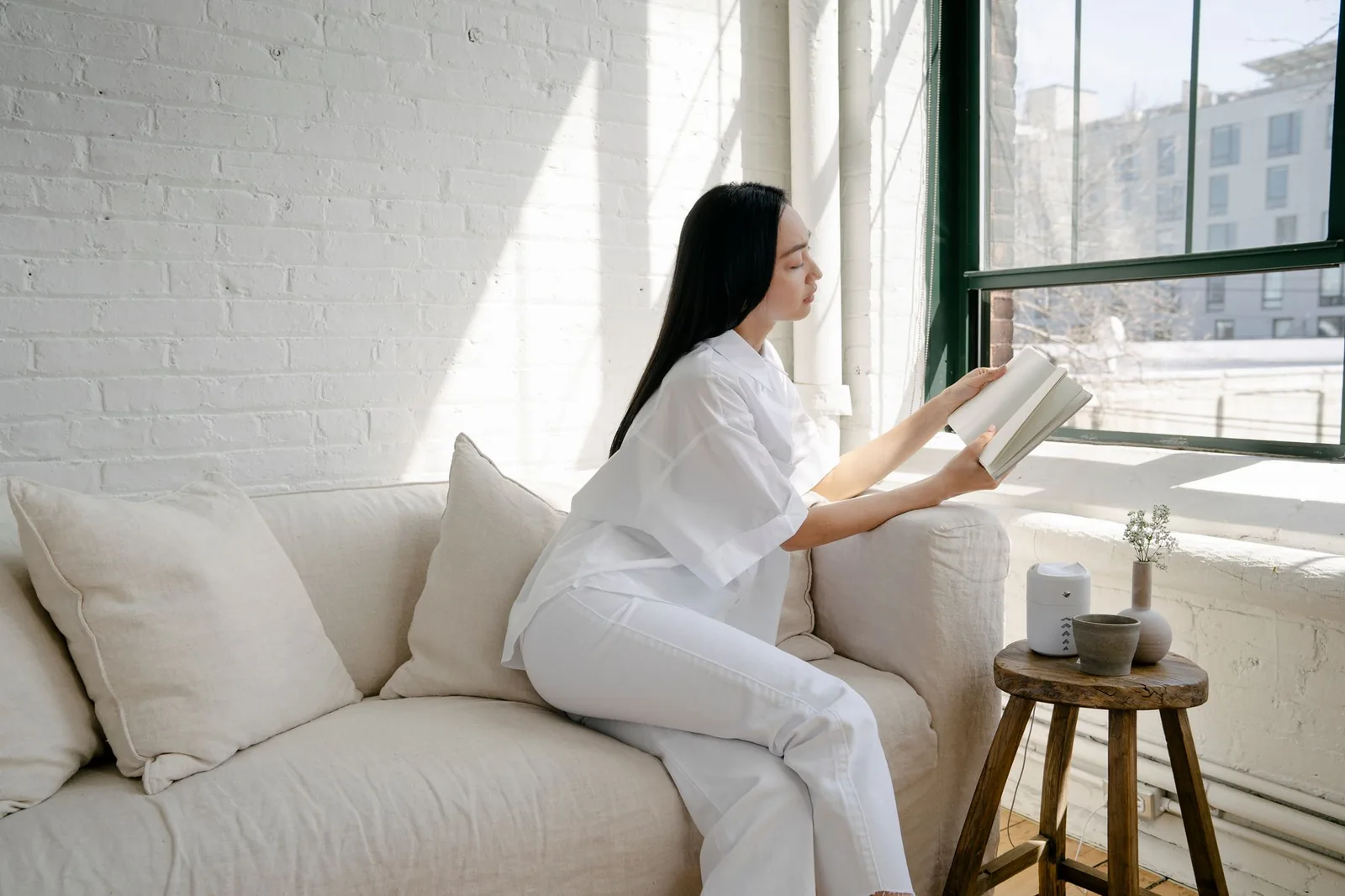 Người phụ nữ ngồi đọc sách bên cửa sổ